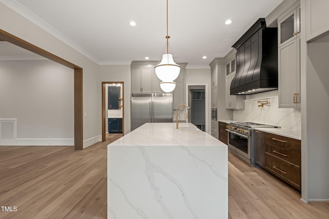 kitchen with a sink, premium range hood, light wood-type flooring, premium appliances, and visible vents