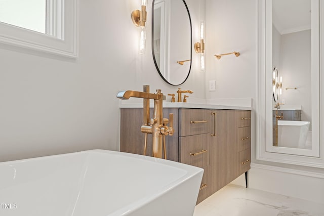 bathroom featuring vanity, ornamental molding, marble finish floor, and a freestanding bath