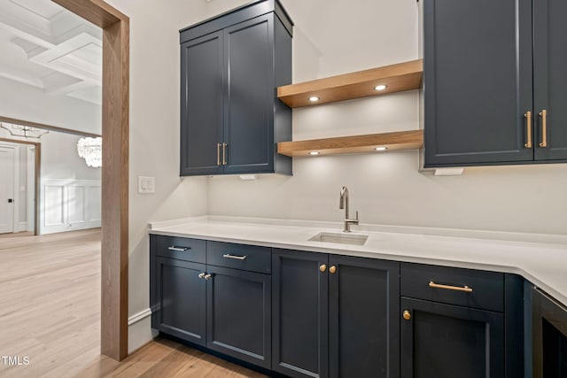 kitchen featuring a sink, light countertops, light wood-style floors, and open shelves