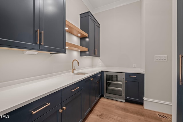 bar featuring crown molding, beverage cooler, bar, a sink, and light wood finished floors