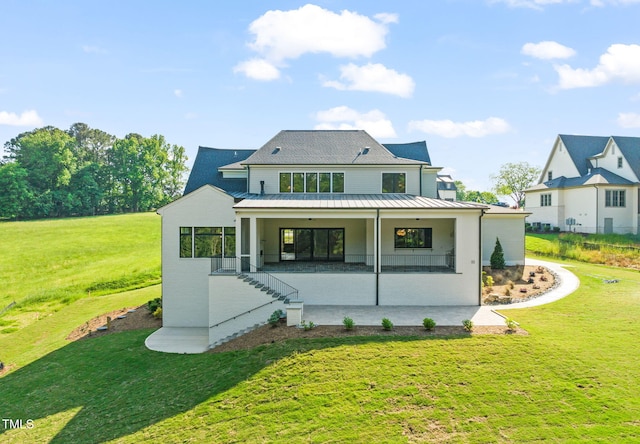 back of property with metal roof, a yard, and a standing seam roof