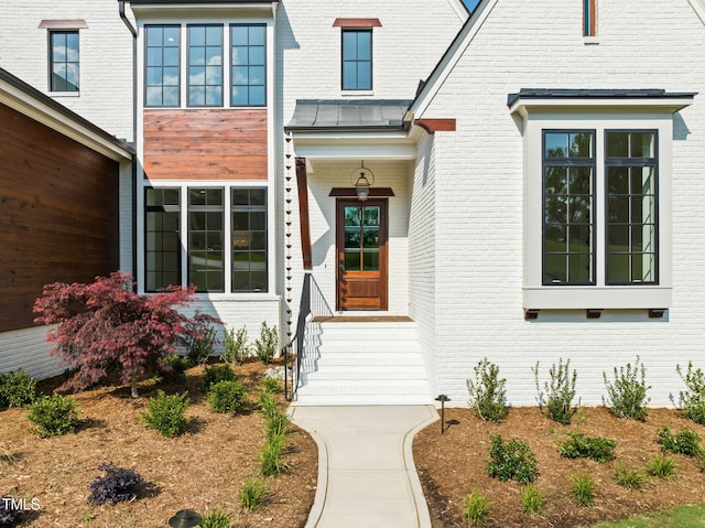 doorway to property with brick siding and a standing seam roof
