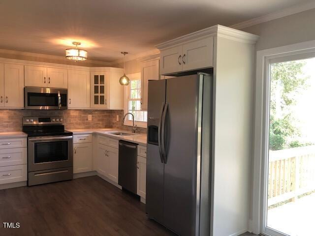 kitchen with stainless steel appliances, a sink, light countertops, tasteful backsplash, and glass insert cabinets