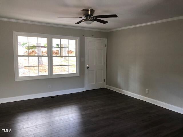 empty room featuring ceiling fan, dark wood-type flooring, baseboards, and crown molding