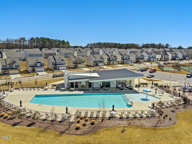 pool with a patio, fence, and a residential view