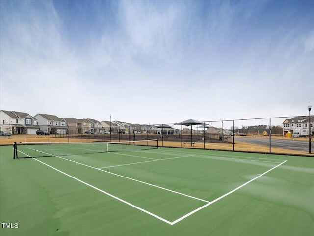 view of tennis court featuring fence and a residential view
