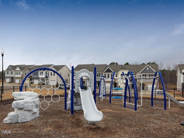 communal playground featuring fence and a residential view