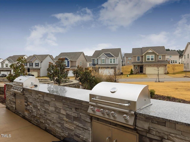 view of patio / terrace featuring a grill, a residential view, and an outdoor kitchen