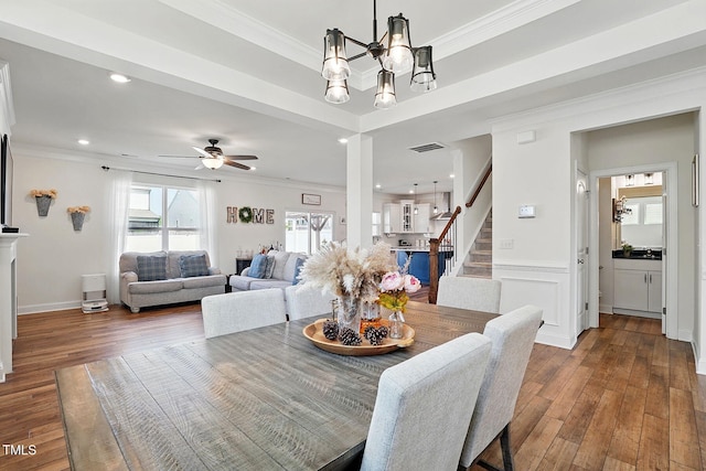 dining space with ceiling fan with notable chandelier, ornamental molding, stairway, and hardwood / wood-style floors