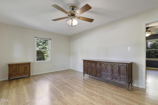 unfurnished room with baseboards, ceiling fan, a wealth of natural light, and light wood finished floors