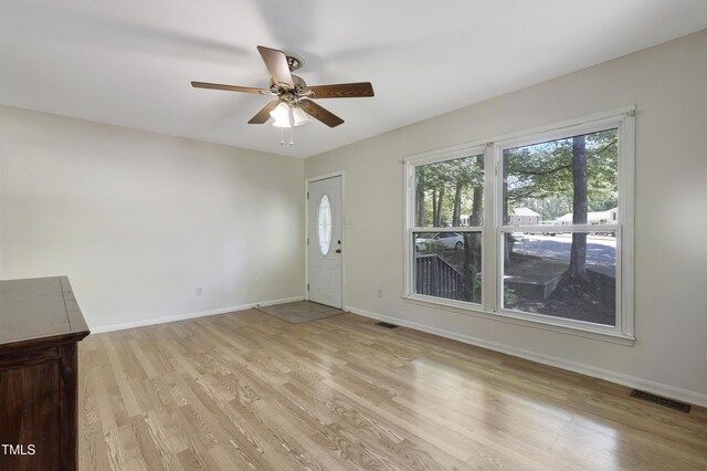 unfurnished living room featuring plenty of natural light, a ceiling fan, light wood-style flooring, and visible vents