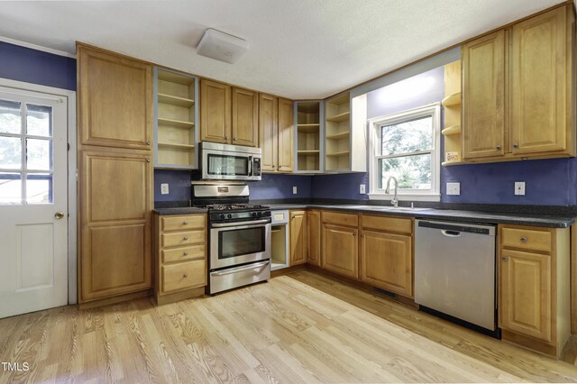 kitchen with open shelves, appliances with stainless steel finishes, dark countertops, and a sink