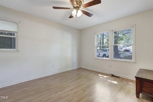 spare room featuring baseboards, light wood-style flooring, ceiling fan, and visible vents
