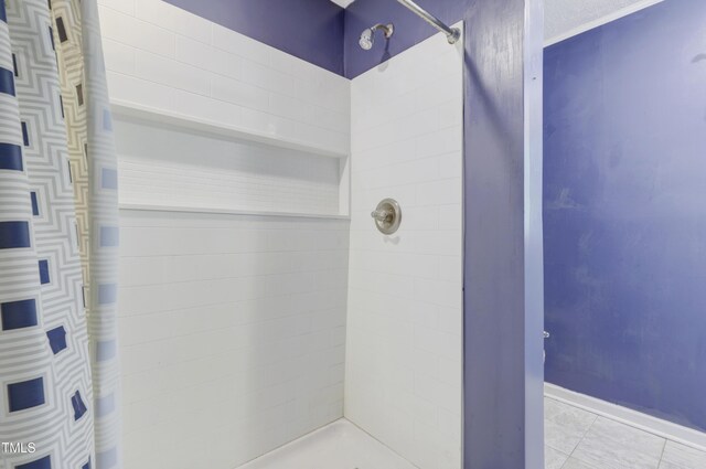 bathroom with baseboards and tiled shower
