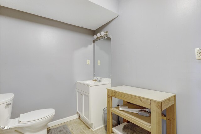 half bathroom featuring toilet, baseboards, and vanity