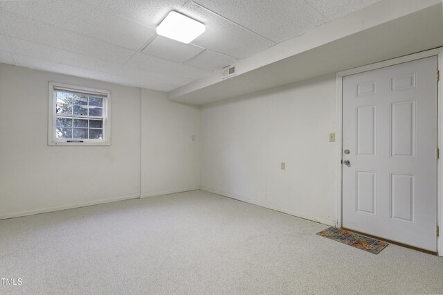 empty room with carpet flooring, baseboards, visible vents, and a drop ceiling