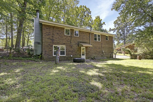 back of house with brick siding, a yard, and a chimney