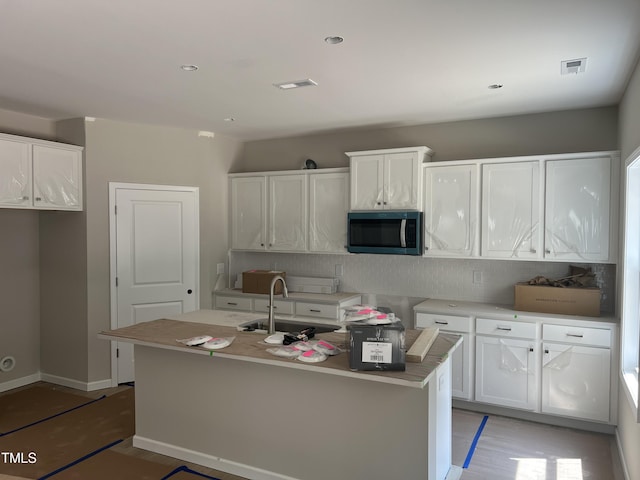 169 Pecan Valley Way, Four Oaks, NC 27524 - kitchen with stainless steel microwave, a sink, decorative backsplash, and white cabinets