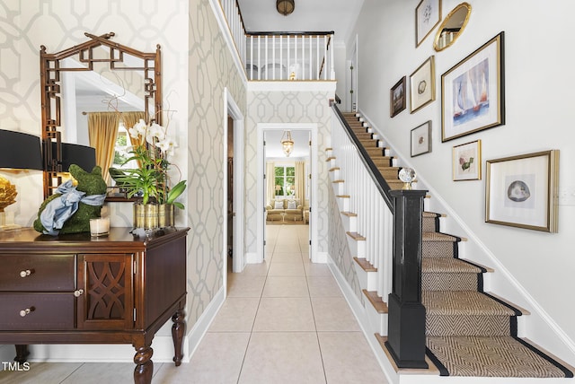 interior space featuring stairs, wallpapered walls, baseboards, and a high ceiling