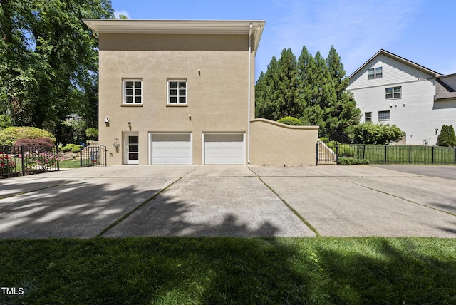 view of side of home featuring a garage, fence, stucco siding, and driveway