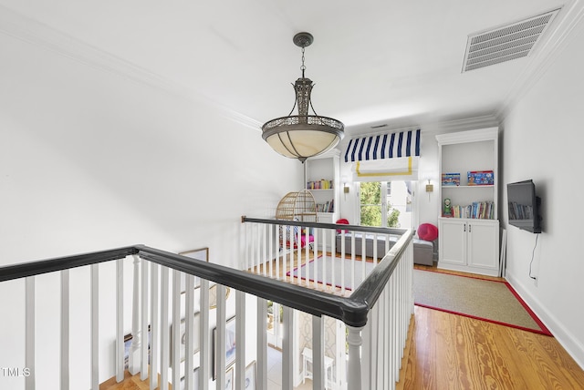 staircase featuring crown molding, wood finished floors, and visible vents