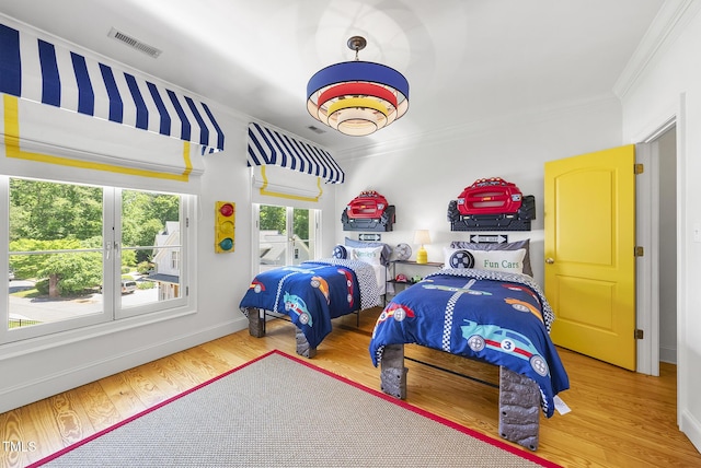 bedroom with baseboards, visible vents, ornamental molding, and wood finished floors