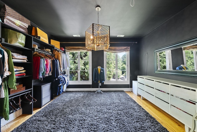 walk in closet featuring visible vents, wood finished floors, and a chandelier
