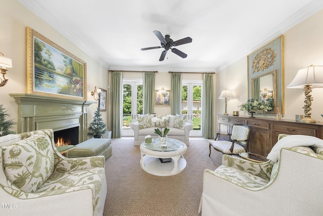 living room featuring a ceiling fan, carpet, a lit fireplace, and ornamental molding