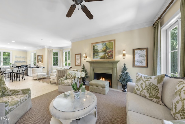 living area featuring crown molding, ceiling fan, a warm lit fireplace, recessed lighting, and tile patterned floors