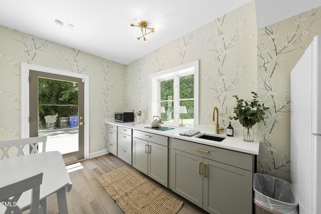 kitchen featuring freestanding refrigerator, plenty of natural light, stainless steel microwave, a sink, and gray cabinetry