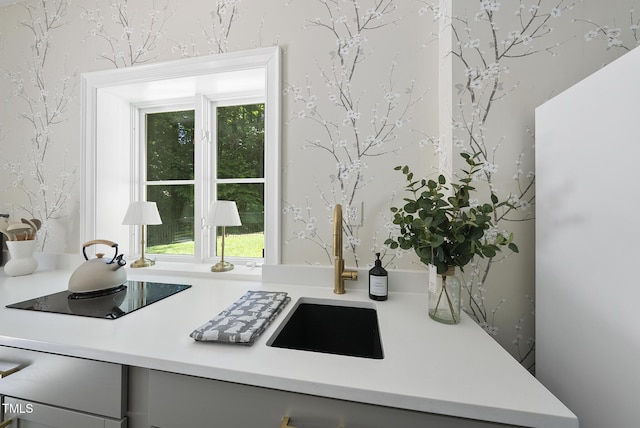 interior details with a sink, light countertops, gray cabinets, and black electric stovetop