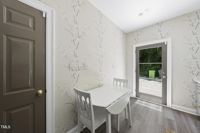 dining space with baseboards, wallpapered walls, and wood finished floors