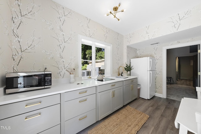 kitchen featuring a sink, gray cabinets, freestanding refrigerator, stainless steel microwave, and visible vents