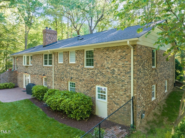 3420 Sheridan Dr, Durham, NC 27707 - view of property exterior featuring a patio, a chimney, brick siding, and roof with shingles