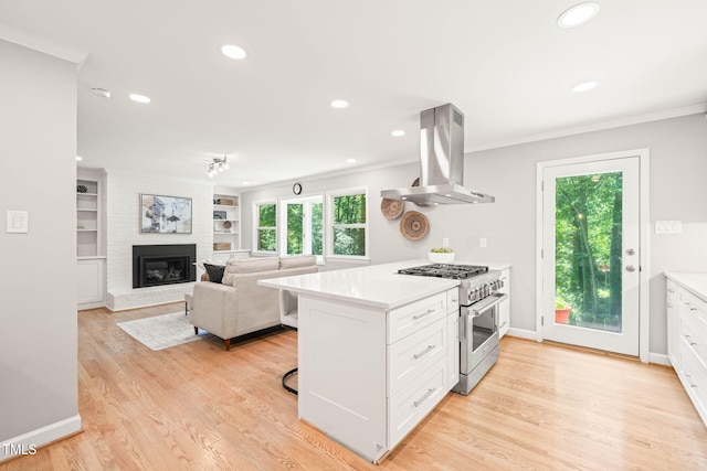 3420 Sheridan Dr, Durham, NC 27707 - kitchen with island range hood, high end range, ornamental molding, a fireplace, and healthy amount of natural light