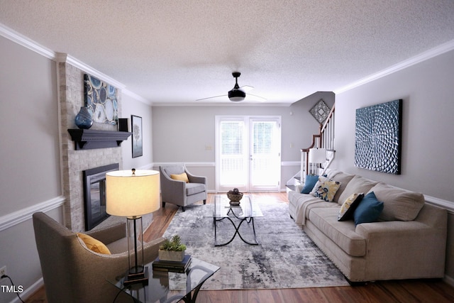 3832 Doeskin Dr, Apex, NC 27539 - living room featuring a textured ceiling, a ceiling fan, crown molding, a large fireplace, and wood finished floors