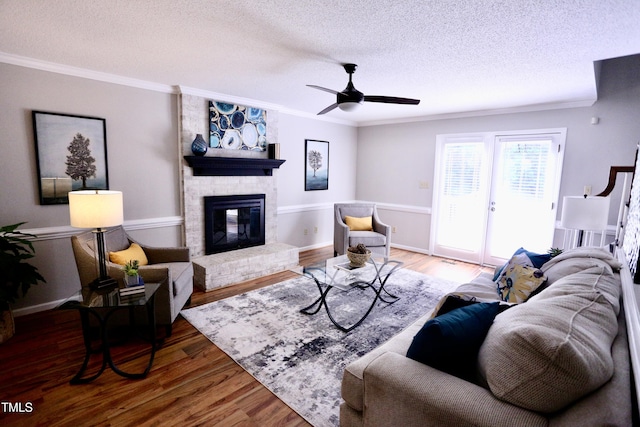 3832 Doeskin Dr, Apex, NC 27539 - living room featuring a textured ceiling, ornamental molding, a brick fireplace, wood finished floors, and ceiling fan