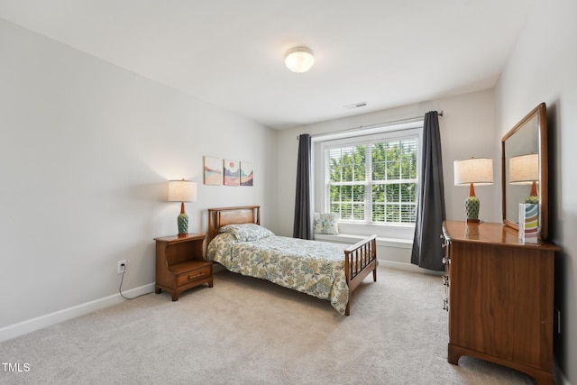 bedroom with visible vents, baseboards, and light carpet