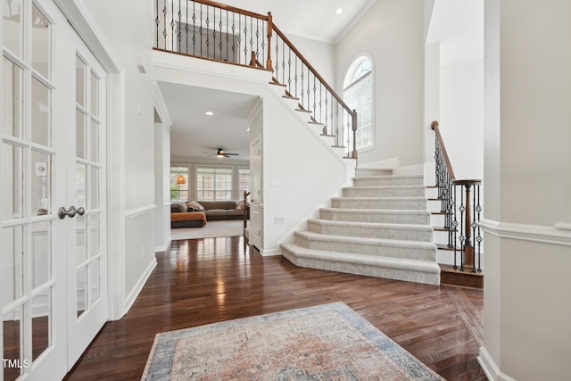 foyer entrance featuring a ceiling fan, wood finished floors, a high ceiling, stairway, and ornamental molding