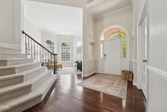 entrance foyer with ornamental molding, a towering ceiling, stairway, and hardwood / wood-style flooring