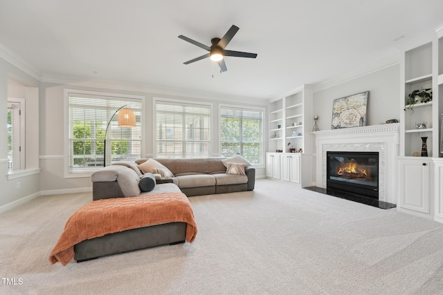 living area with carpet floors, ornamental molding, a ceiling fan, and a healthy amount of sunlight