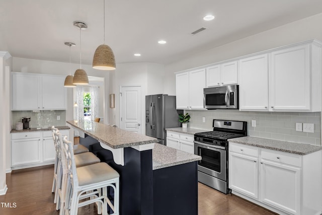3801 Althorp Dr, Raleigh, NC 27616 - kitchen featuring backsplash, a kitchen island, visible vents, appliances with stainless steel finishes, and dark wood finished floors