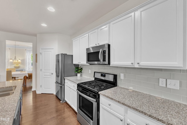 3801 Althorp Dr, Raleigh, NC 27616 - kitchen with dark wood-style flooring, white cabinetry, tasteful backsplash, light stone counters, and stainless steel appliances