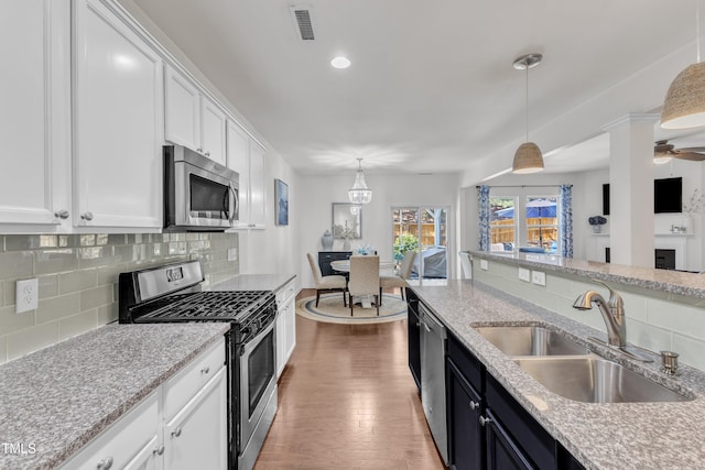 3801 Althorp Dr, Raleigh, NC 27616 - kitchen featuring decorative backsplash, wood finished floors, white cabinets, a sink, and stainless steel appliances
