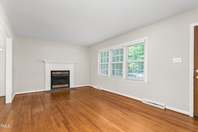 2917 Trail Six, Burlington, NC 27215 - unfurnished living room with wood finished floors, baseboards, and a glass covered fireplace