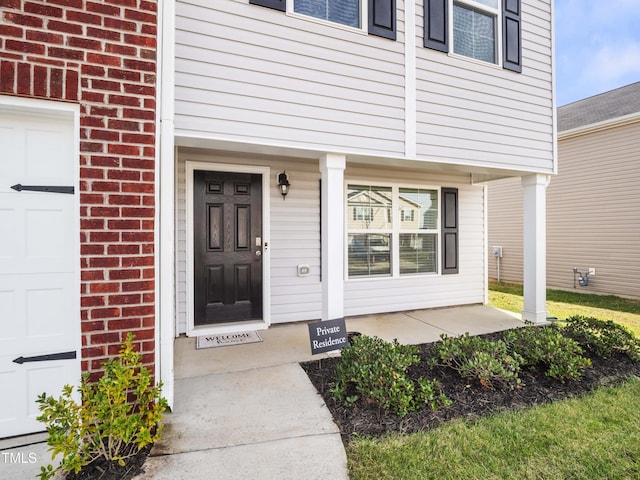 6858 Keeneland Dr, Whitsett, NC 27377 - entrance to property featuring brick siding, a garage, and covered porch