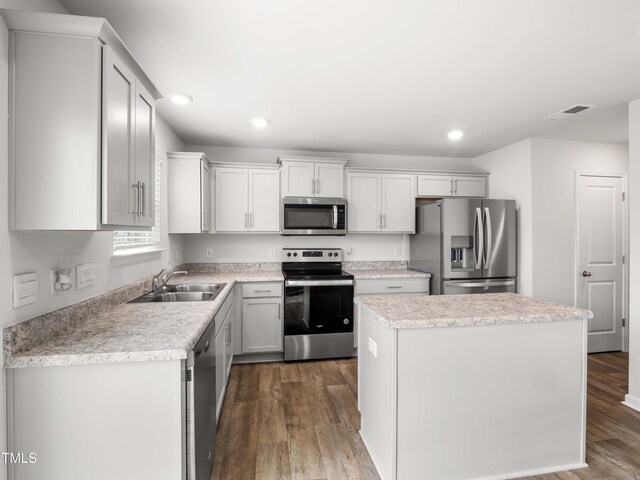 6858 Keeneland Dr, Whitsett, NC 27377 - kitchen featuring a kitchen island, dark wood-type flooring, light countertops, a sink, and stainless steel appliances
