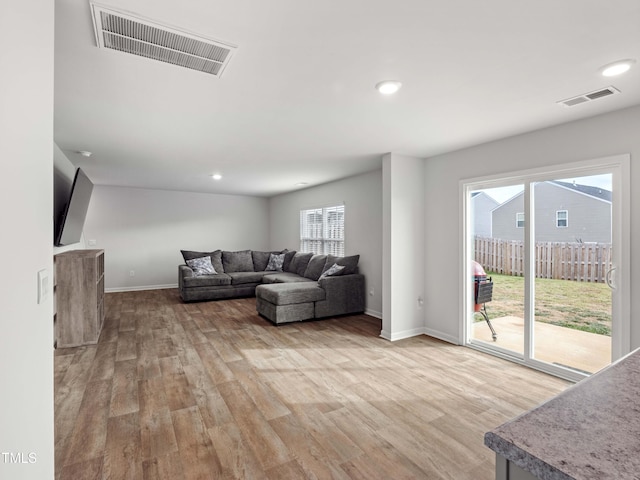 6858 Keeneland Dr, Whitsett, NC 27377 - living room featuring light wood-style floors, a healthy amount of sunlight, and visible vents