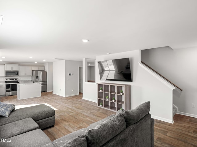 6858 Keeneland Dr, Whitsett, NC 27377 - living room featuring light wood-style floors, baseboards, recessed lighting, and stairs