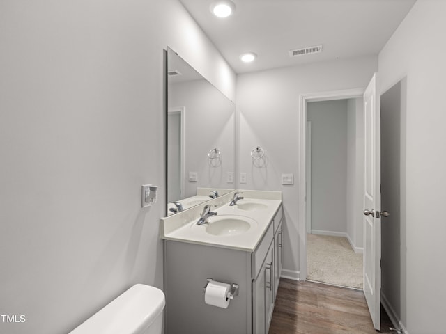 6858 Keeneland Dr, Whitsett, NC 27377 - bathroom featuring a sink, toilet, wood finished floors, and visible vents
